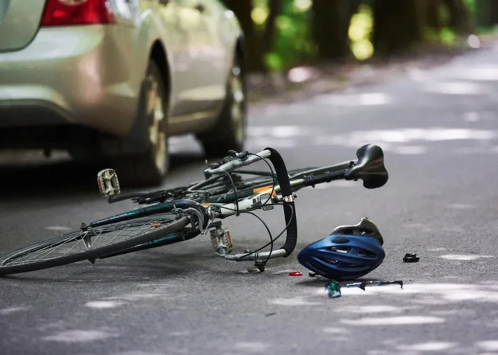 Rower i kask rowerowy leżące na drodze przed samochodem