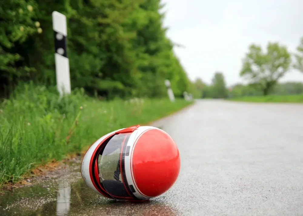 Czerwono-biały kask motocyklowy leżący na mokrej wiejskiej drodze