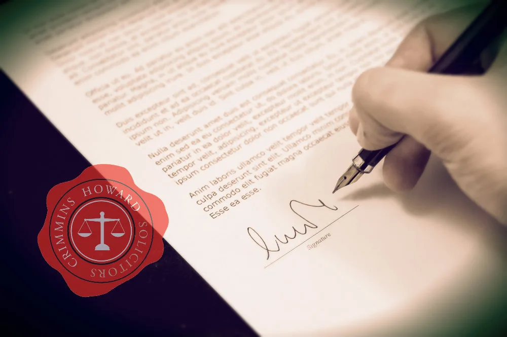 A hand signing a document with a fountain pen, the Crimmins Howard seal beside it
